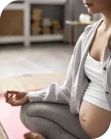 mujer embarazada haciendo ejercicio relajante en casa-cabecera sección mamás moon croos con imagen de marta y nuria en la playa-Moon training
